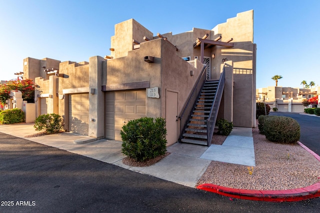 view of building exterior featuring a garage, a residential view, and stairs