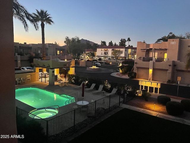 pool at dusk featuring a residential view, a patio, a community pool, and fence