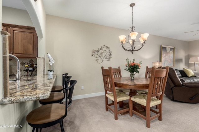 dining room featuring light carpet, baseboards, and an inviting chandelier