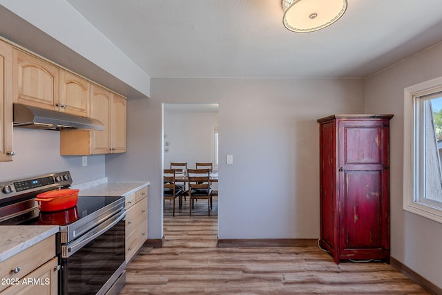 kitchen with stainless steel range with electric stovetop, under cabinet range hood, light brown cabinetry, and light countertops