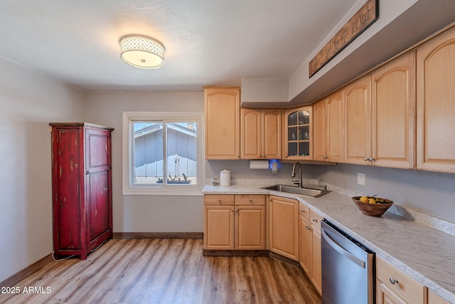 kitchen with stainless steel dishwasher, a sink, light brown cabinets, and light wood-style flooring