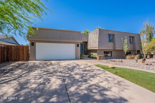 view of front property featuring brick siding, mansard roof, concrete driveway, and fence