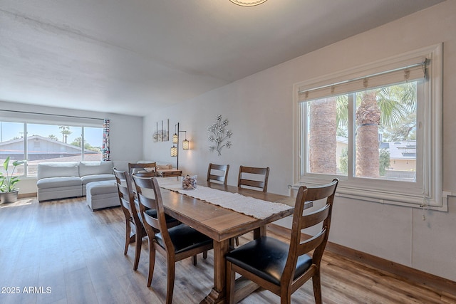 dining space with light wood-type flooring and baseboards