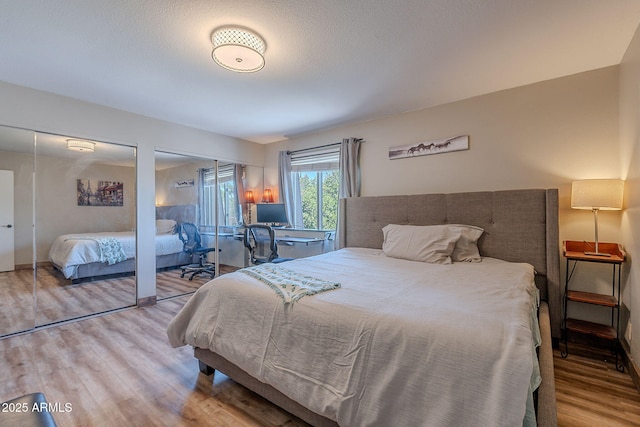 bedroom with multiple closets, wood finished floors, and baseboards
