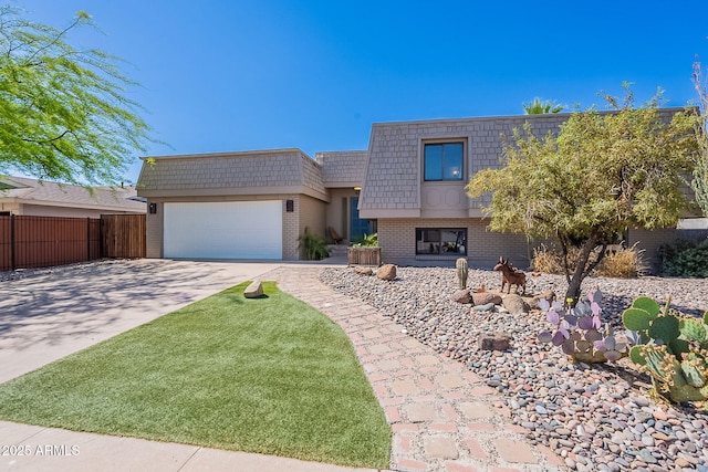 view of front property with brick siding, mansard roof, an attached garage, driveway, and fence