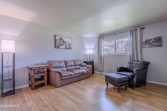 living area featuring light wood-style floors, baseboards, and a textured ceiling