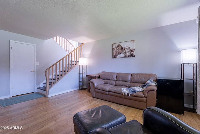 living room featuring wood finished floors, stairway, a textured ceiling, and baseboards