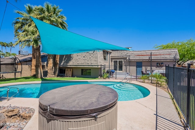 view of swimming pool with fence, a trampoline, a hot tub, and a patio