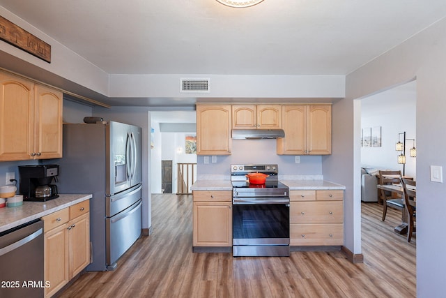 kitchen featuring appliances with stainless steel finishes, light brown cabinets, light wood-style floors, and light countertops