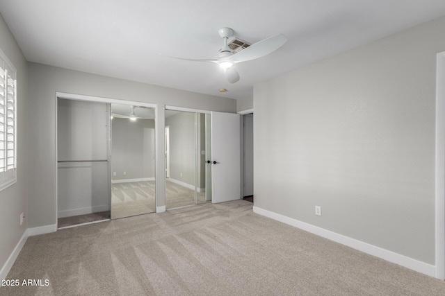 unfurnished bedroom with two closets, carpet floors, a ceiling fan, and baseboards