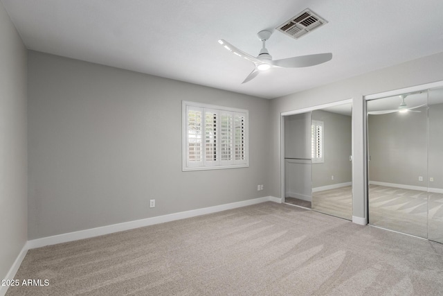 unfurnished bedroom with multiple closets, light colored carpet, baseboards, and ceiling fan