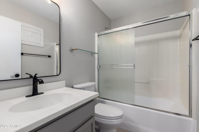 full bath with toilet, vanity, and shower / bath combination with glass door