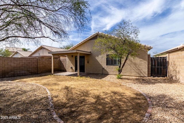 back of house with stucco siding, a patio, and a fenced backyard