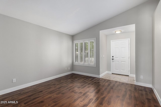 foyer entrance with vaulted ceiling, wood finished floors, and baseboards