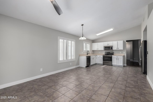 kitchen with appliances with stainless steel finishes, vaulted ceiling, light countertops, white cabinets, and baseboards