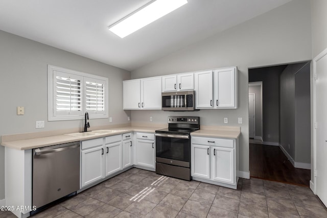 kitchen featuring stainless steel appliances, a sink, vaulted ceiling, white cabinetry, and light countertops