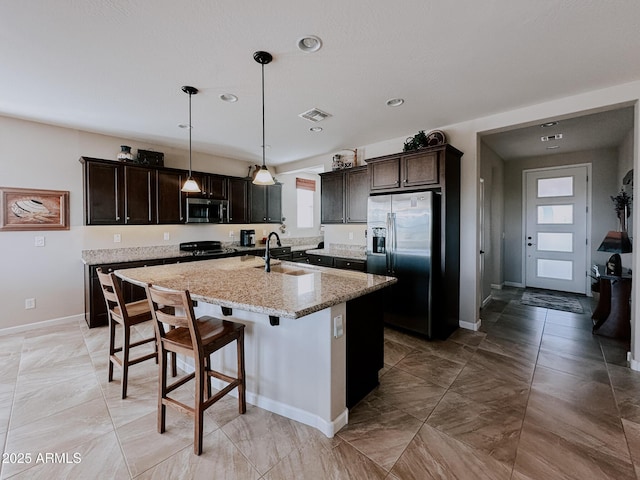 kitchen featuring sink, dark brown cabinetry, stainless steel appliances, and a kitchen island with sink