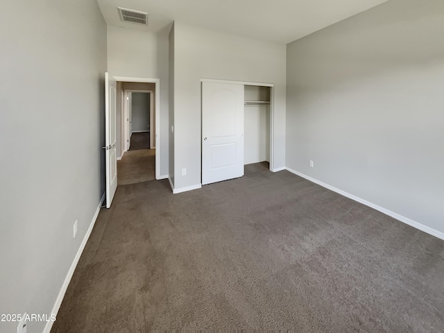 unfurnished bedroom featuring dark carpet and a closet