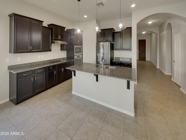 kitchen featuring appliances with stainless steel finishes, decorative light fixtures, an island with sink, sink, and a breakfast bar area
