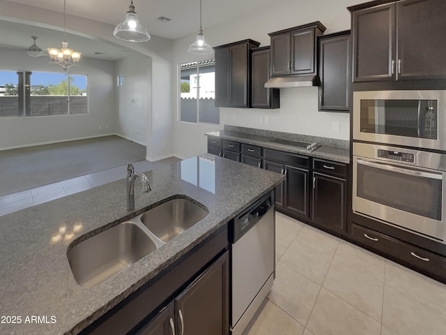kitchen featuring stainless steel appliances, sink, hanging light fixtures, and dark stone countertops