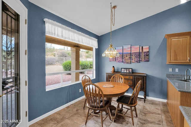 dining area with an inviting chandelier, lofted ceiling, and sink