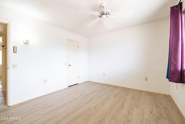 spare room with light wood-style floors, a ceiling fan, baseboards, and a textured ceiling