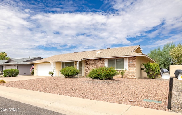 ranch-style home with a shingled roof, brick siding, driveway, and an attached garage