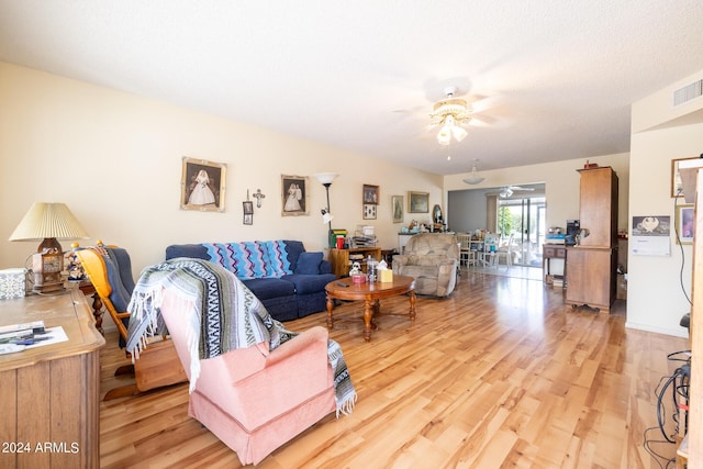 living room with ceiling fan, light hardwood / wood-style floors, and a textured ceiling