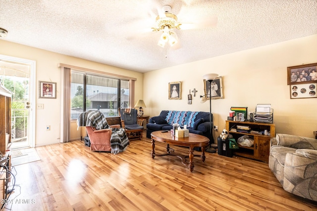 living room with a textured ceiling, ceiling fan, and light wood finished floors