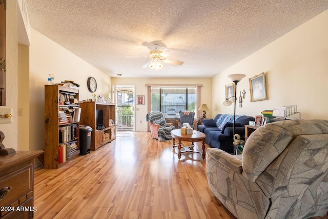 living room featuring a textured ceiling, ceiling fan, and light hardwood / wood-style floors