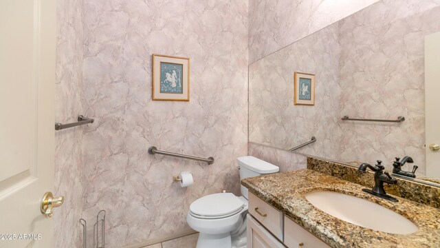 half bath featuring vanity, tile patterned flooring, and toilet