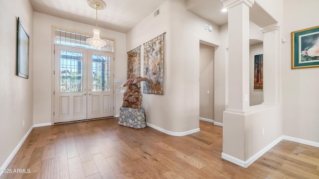 entrance foyer with light wood-style flooring, visible vents, baseboards, and an inviting chandelier