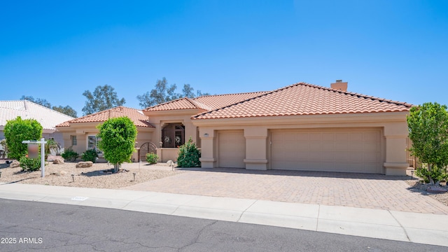mediterranean / spanish house featuring stucco siding, driveway, a tiled roof, and a garage