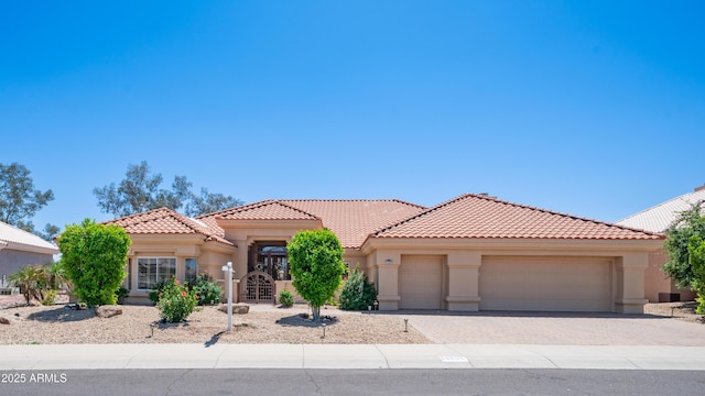 mediterranean / spanish-style home with stucco siding, an attached garage, driveway, and a tiled roof