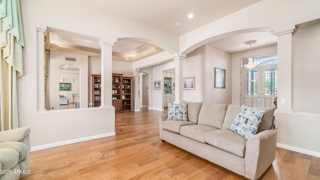 living room with light wood finished floors, arched walkways, decorative columns, visible vents, and recessed lighting