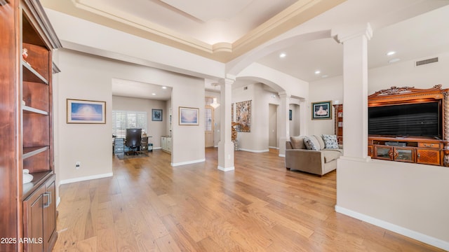 living area with recessed lighting, light wood finished floors, ornate columns, visible vents, and arched walkways