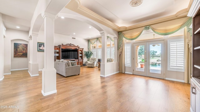 living room with a fireplace, arched walkways, light wood finished floors, and ornate columns