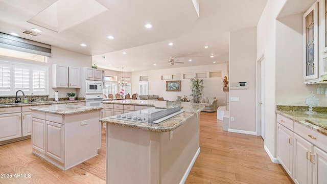 kitchen with a sink, light wood-style floors, white appliances, a large island, and visible vents