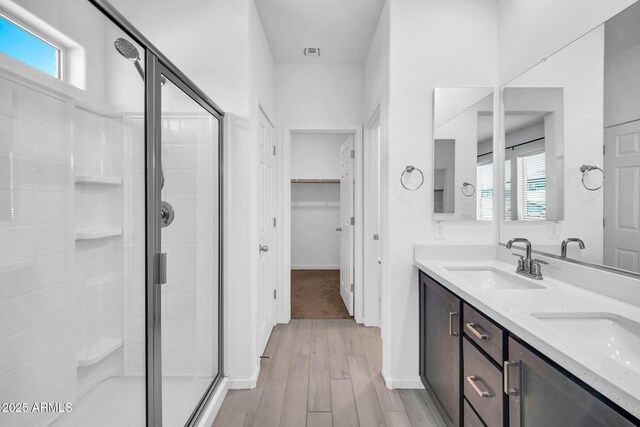 bathroom with a sink, a shower stall, wood finished floors, and a wealth of natural light