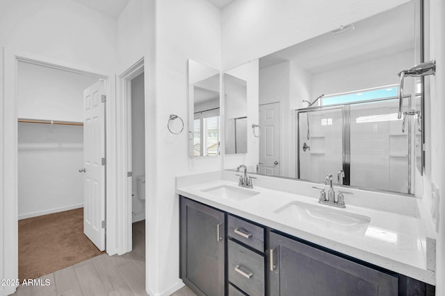 bathroom featuring a sink, a spacious closet, toilet, and a shower stall