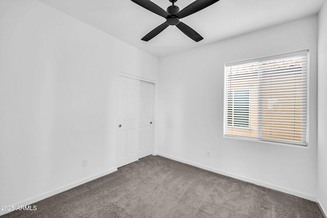 carpeted empty room with ceiling fan and baseboards