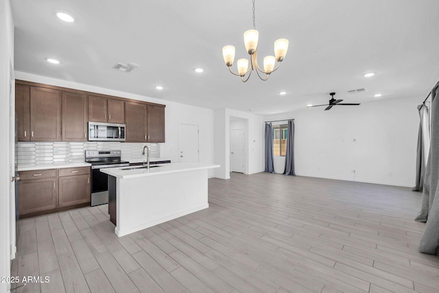 kitchen with visible vents, open floor plan, light countertops, a sink, and stainless steel appliances