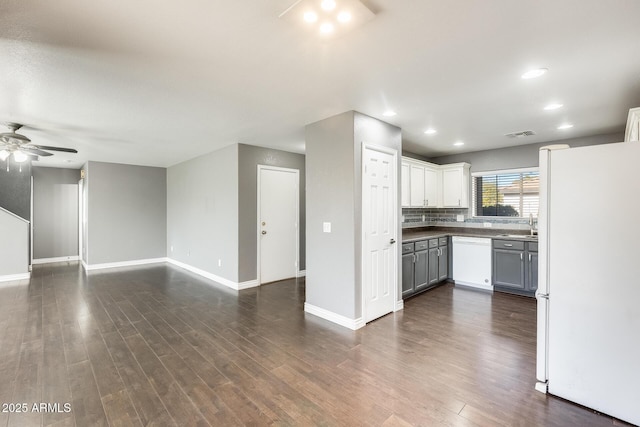 kitchen featuring dark wood-type flooring, gray cabinetry, ceiling fan, white appliances, and backsplash