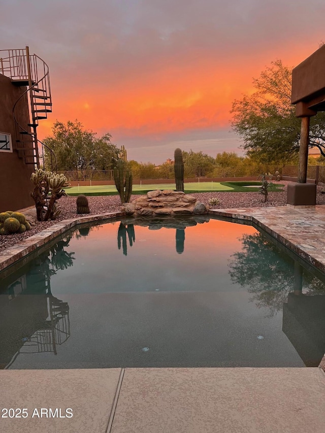 pool at dusk featuring a patio