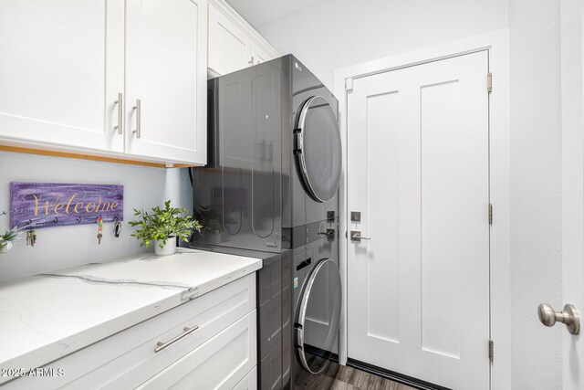 clothes washing area featuring stacked washer and clothes dryer and cabinet space
