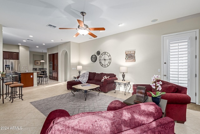 tiled living room featuring ceiling fan and sink