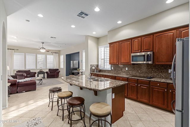 kitchen with a healthy amount of sunlight, appliances with stainless steel finishes, dark stone counters, and a kitchen bar