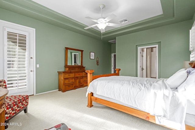 carpeted bedroom featuring a raised ceiling and ceiling fan