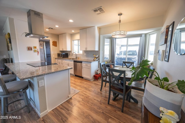 kitchen with white cabinetry, hanging light fixtures, appliances with stainless steel finishes, and island exhaust hood