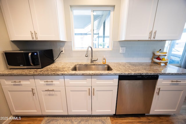 kitchen with sink, light stone countertops, white cabinets, and appliances with stainless steel finishes